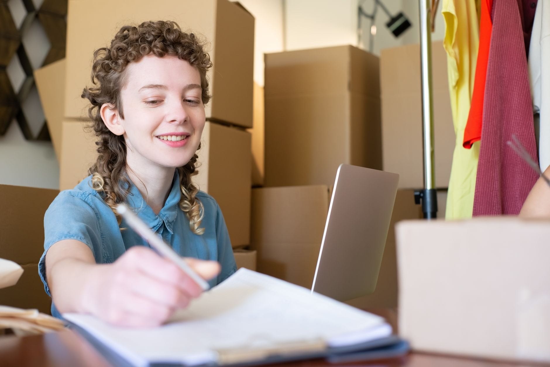 Smiling young woman managing a small business with laptop and packages